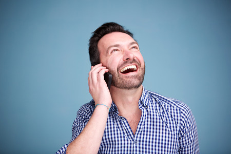Close up portrait of happy man talking on mobile phone and looking upの写真素材