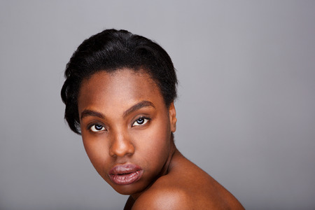 Close up portrait of beautiful black woman with bare shoulders against gray backgroundの写真素材