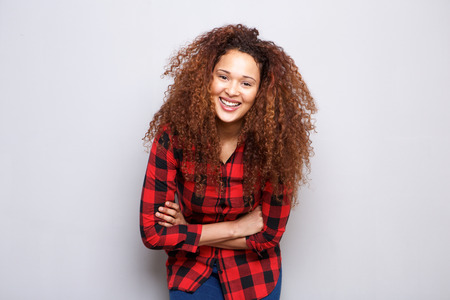 Portrait of happy young woman with curly hair smiling against gray backgroundの写真素材