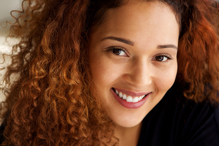 Close up portrait of beautiful mixed race woman with curly hair smilingの写真素材