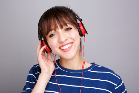 Close up portrait of smiling young woman listening to music with headphonesの写真素材
