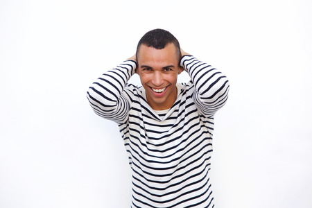 Portrait of happy young man laughing with hands behind head against isolated white background