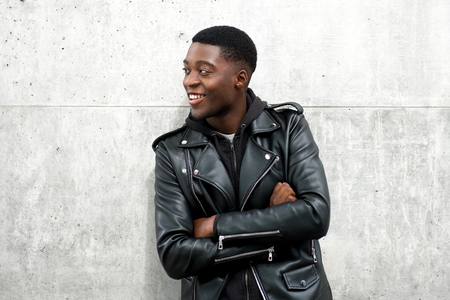 Portrait of happy black guy in leather jacket with arms crossedの写真素材