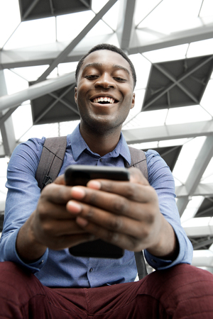 Portrait of young african man looking at cellphoneの写真素材