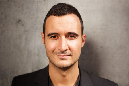 Close up head portrait of latin man in his 30s against gray background