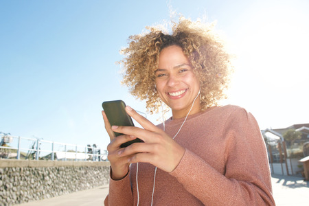 Portrait of carefree woman listening to music with earphones and smart phone