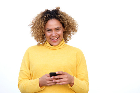 Portrait of happy young african american woman smiling against isolated white background with mobile...