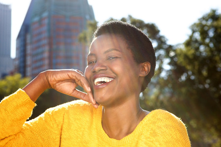 Close up portrait of healthy young black woman laughing outdoors