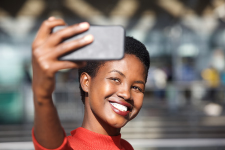 Close up portrait of happy african american woman taking selfie with mobile phone cameraの写真素材