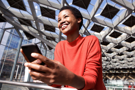 Candid portrait of smiling african american woman holding mobile phone