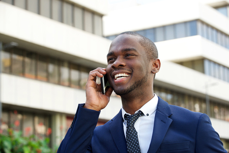 Close up portrait of smiling young african american businessman talking with cellphone in cityの写真素材