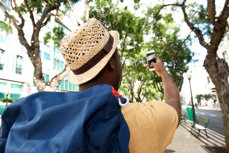 Portrait from behind of african american male tourist taking selfieの写真素材