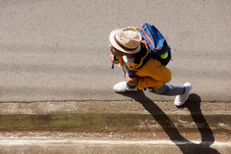 Portrait from above of male hiker with backpack walking on streetの写真素材