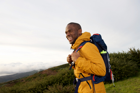 Side portrait of happy male backpacker walking in nature with bagの写真素材