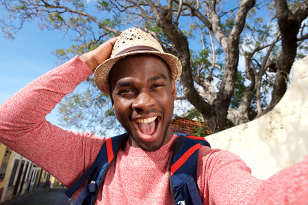Close up portrait of happy african american travel man taking selfieの写真素材