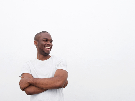 Portrait of happy young african american man laughing with arms crossed against white backgroundの写真素材