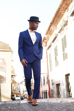 Full body portrait of african american male model in vintage suit and hat walking in cityの写真素材