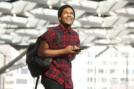 Portrait of smiling african american man with mobile phone and bag looking up