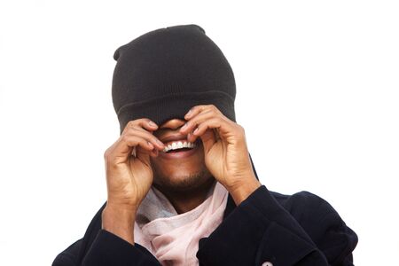 Close up fun portrait of african american man laughing while covering face with beanie