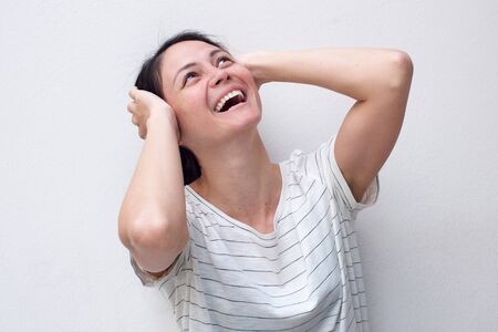 Portrait of cheerful young asian woman laughing with hands behind head and looking upの写真素材