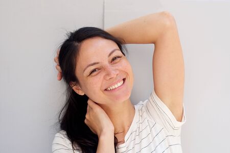 Close up portrait of smiling young asian woman with hands behind head