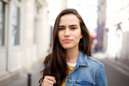 Close up portrait of beautiful young brown hair woman standing in cityの写真素材