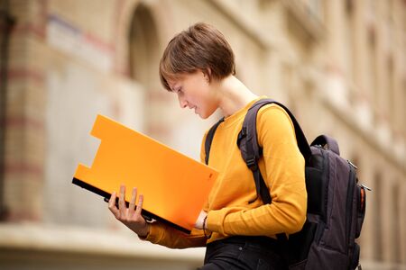 Portrait of female college student reading book on campusの写真素材