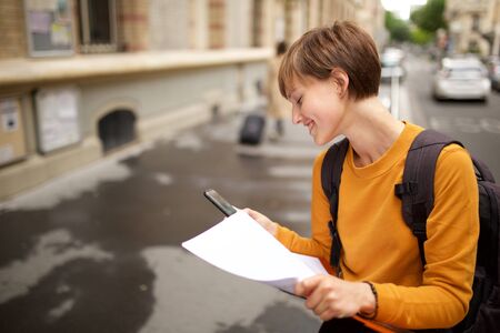 Close up portrait of female college student sitting outside looking at papersの写真素材