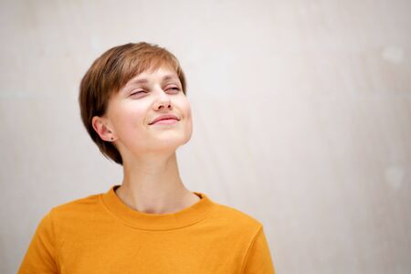 Close up portrait of attractive short hair young woman smiling with eyes closedの写真素材