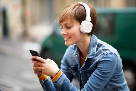Close up portrait of young woman smiling with mobile phone and headphones