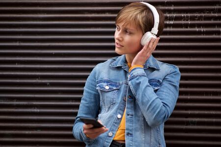 Portrait of cool young woman relaxing with cellphone and headphonesの写真素材