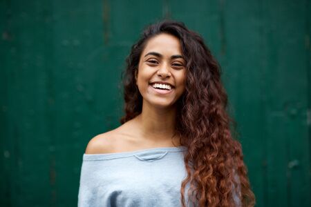 Horizontal front portrait of happy young Indian woman laughing against green backgroundの写真素材