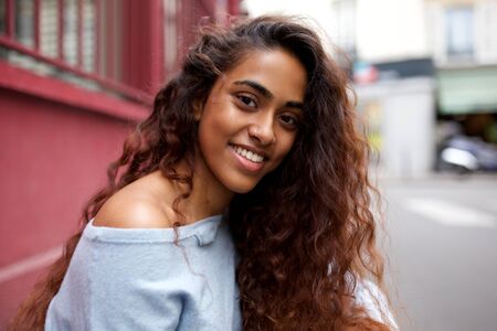 Close up portrait of beautiful young Indian woman smiling outside in cityの写真素材