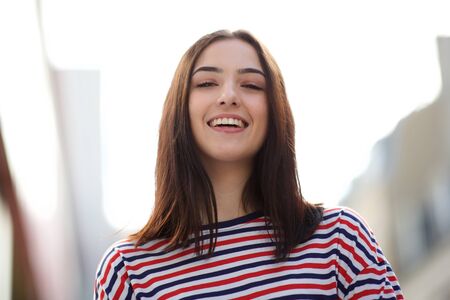 Close up front portrait of smiling young woman with striped shirt