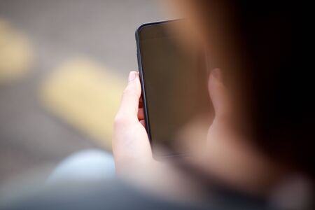 Close up portrait from behind of female hands holding mobile phone