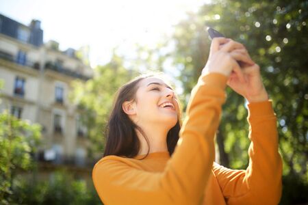 Portrait of cheerful young woman taking selfie outside in park