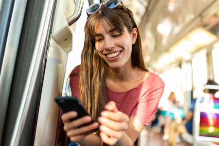 Portrait of smiling young woman looking at mobile phone in the train