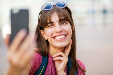 Close up portrait of happy smiling young woman taking selfie with cellphoneの写真素材