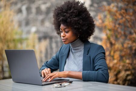 Portrait of serious young black business woman sitting with laptopの写真素材