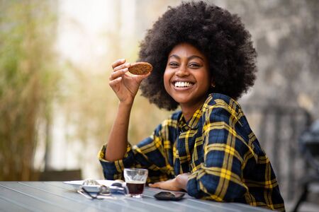 Close up portrait of happy young black woman holding a cookieの写真素材