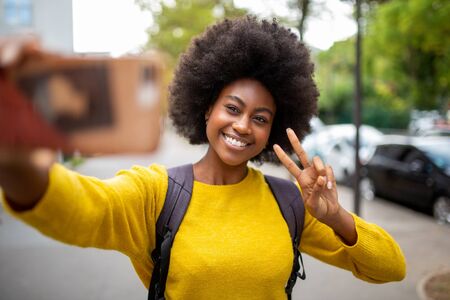 Portrait of smiling afro american woman taking selfie with mobile phone outdoorsの写真素材