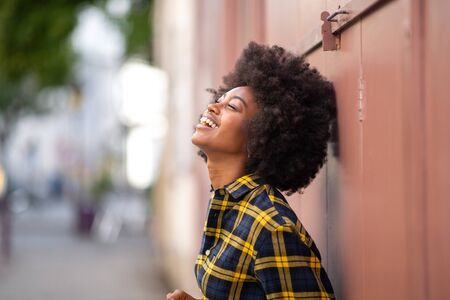 Side portrait of happy young woman laughing and looking upの写真素材