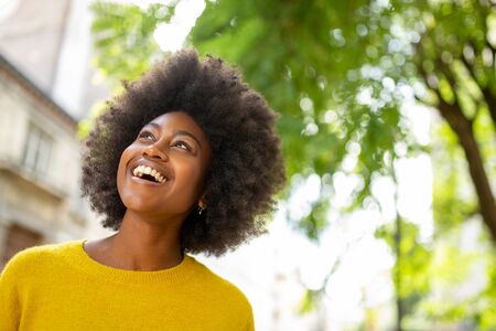 Portrait of beautiful young afro american woman laughing outside