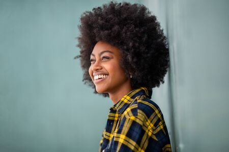 Close up side of happy young black woman with afro hair by green wallの写真素材