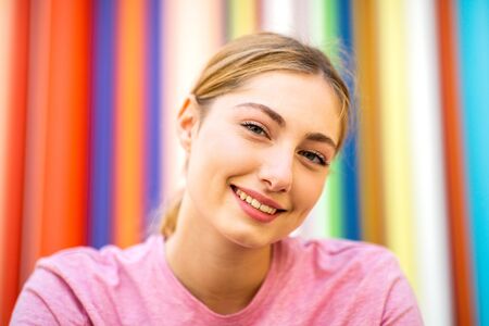Close up portrait of smiling teen girl with blond hair by colorful backgroundの写真素材