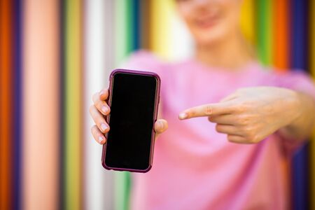 Close up portrait of teen girl pointing to mobile phone screenの写真素材