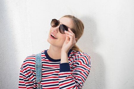 Close up portrait of pretty blond girl with sunglasses by white backgroundの写真素材
