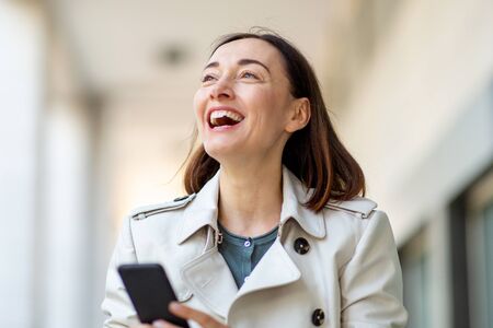 Close up portrait of happy older woman laughing with mobile phoneの写真素材