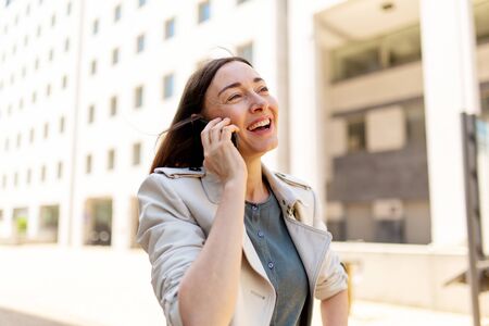 Portrait smiling attractive woman outside in city with cellphoneの写真素材