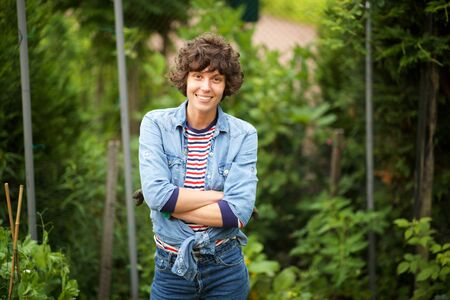 Portrait of smiling woman in garden with arms crossedの写真素材